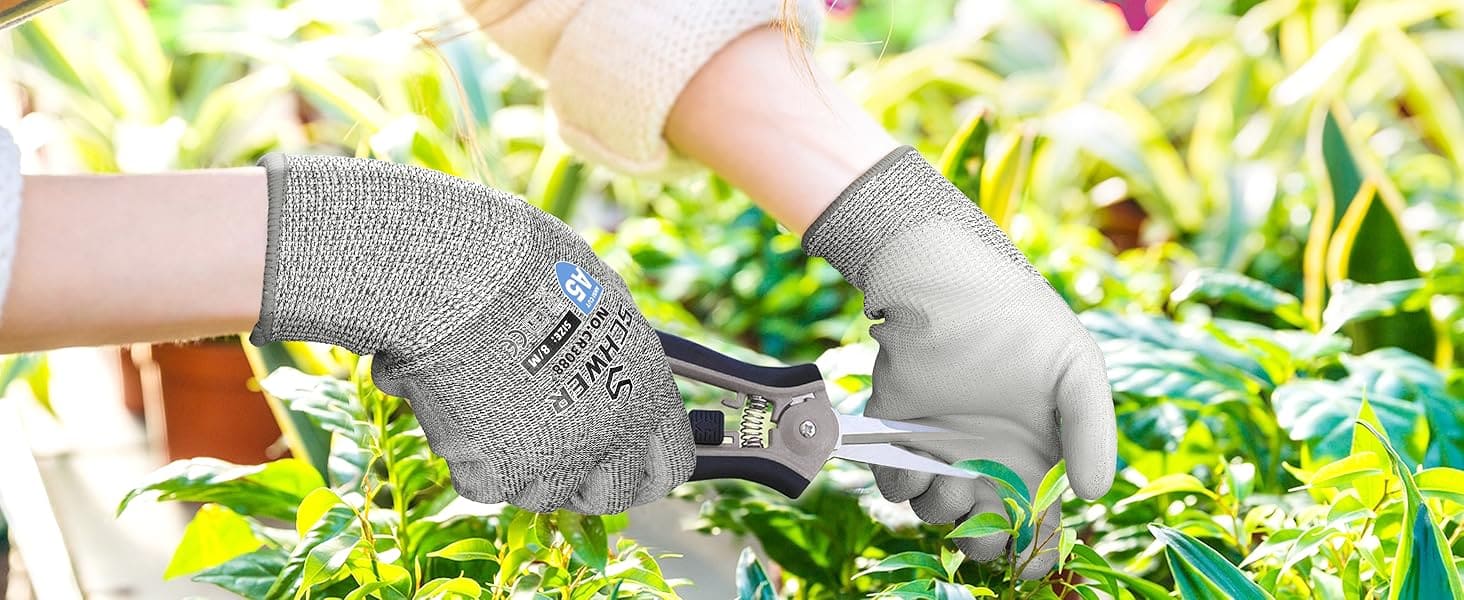 Person wearing gardening gloves holding garden shears in a garden setting
