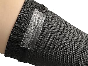 Black mesh bandage on a person's arm with a clear adhesive patch.