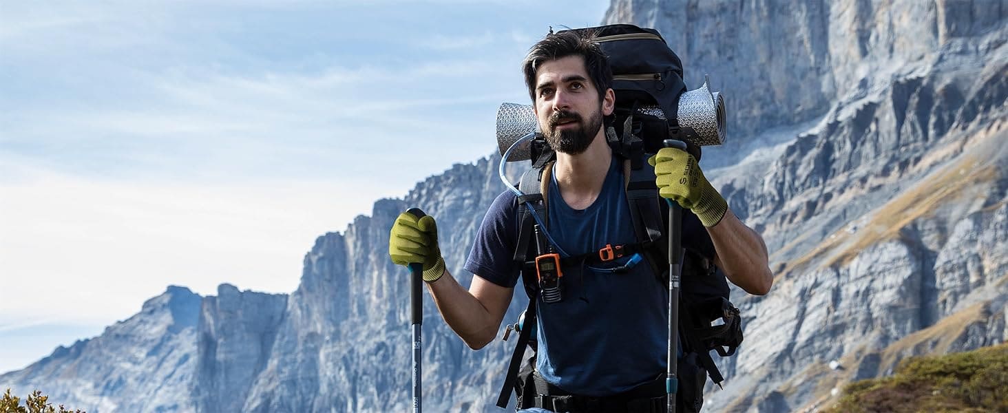Man hiking with a backpack and trekking poles against a mountainous landscape