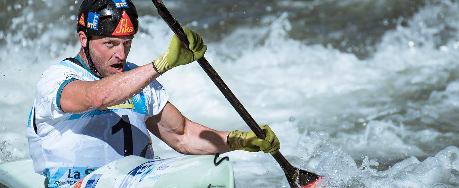 Person kayaking in rough water wearing a helmet and gloves