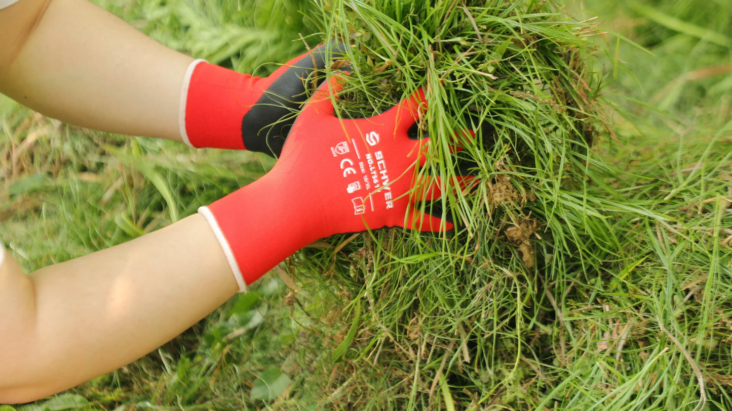 Red protective gloves pulling grass outdoors