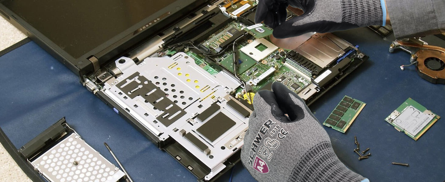 Person repairing a laptop with open casing on a blue mat