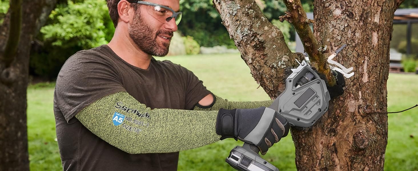 Person using a power tool to trim a tree branch outdoors