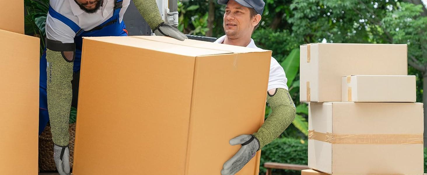 Two workers handling large cardboard boxes outdoors with greenery in the background