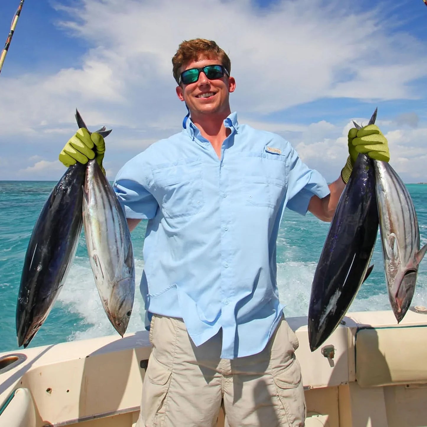 Man wearing Schwergloves work gloves holding four large fresh fish on a boat in clear blue ocean