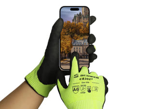 Person holding a phone with a castle in the background wearing green and black gloves.