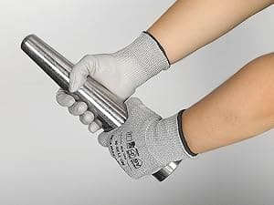 Person wearing gray gloves holding a metal cylindrical object against a light gray background