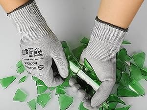 Person wearing safety gloves cutting green glass with a tool
