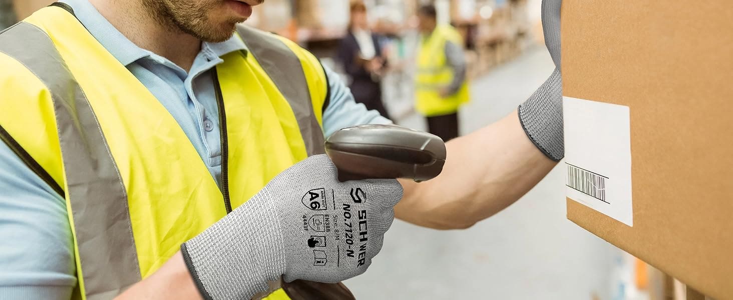 Person in a yellow safety vest and gray gloves handling a cardboard box with a barcode in an indoor setting.