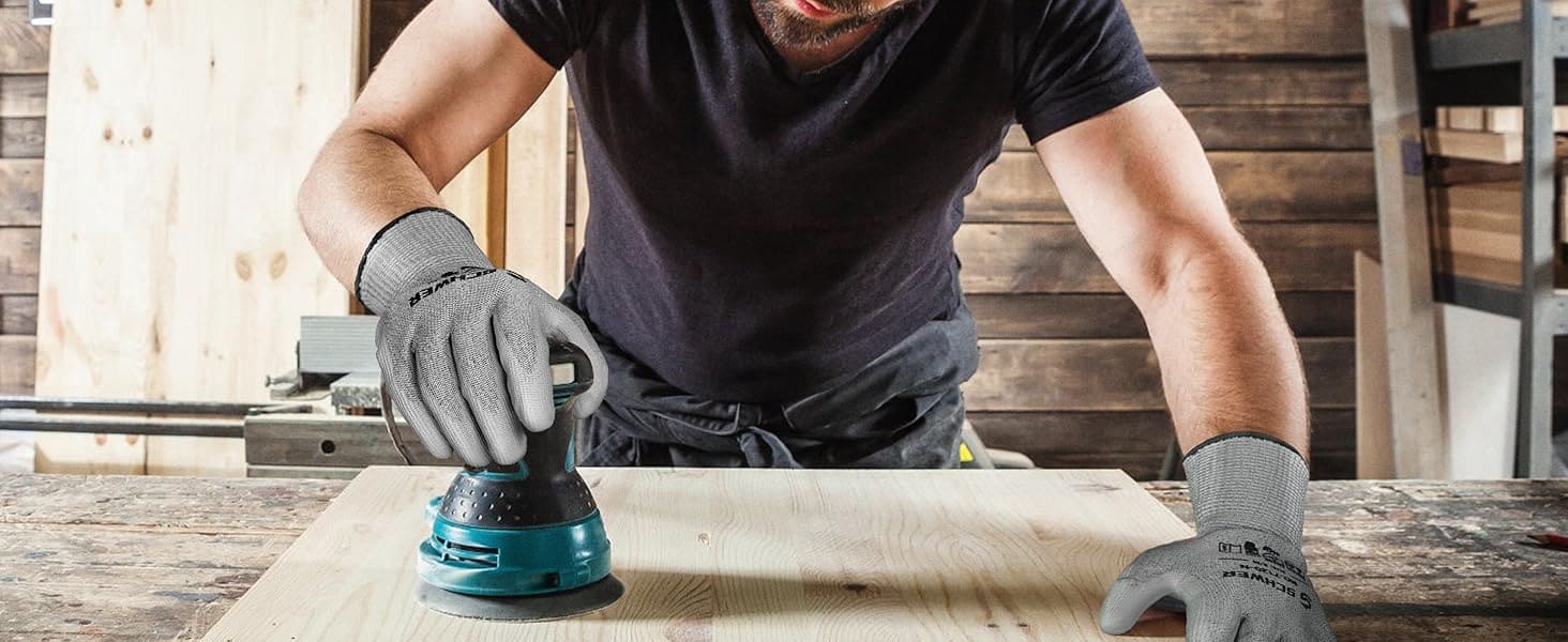 Person sanding a wooden surface with a sander in a workshop setting
