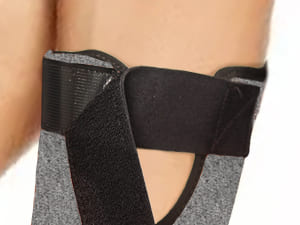 Black and gray ankle support brace on a person's leg with a white background
