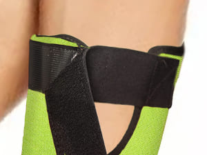 Close-up of a green and black wrist support brace on a person's wrist.