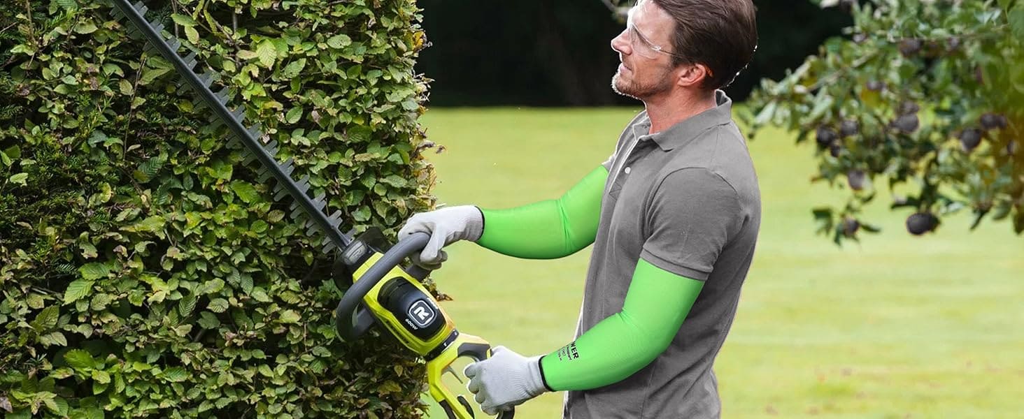 Person using a hedge trimmer to trim a bush in a garden setting