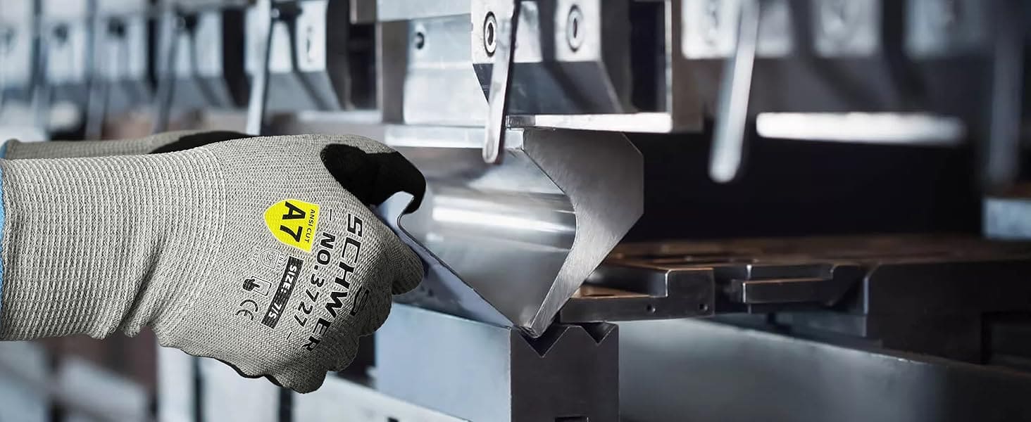 Hand wearing a gray glove with a yellow label holding a metal bracket.