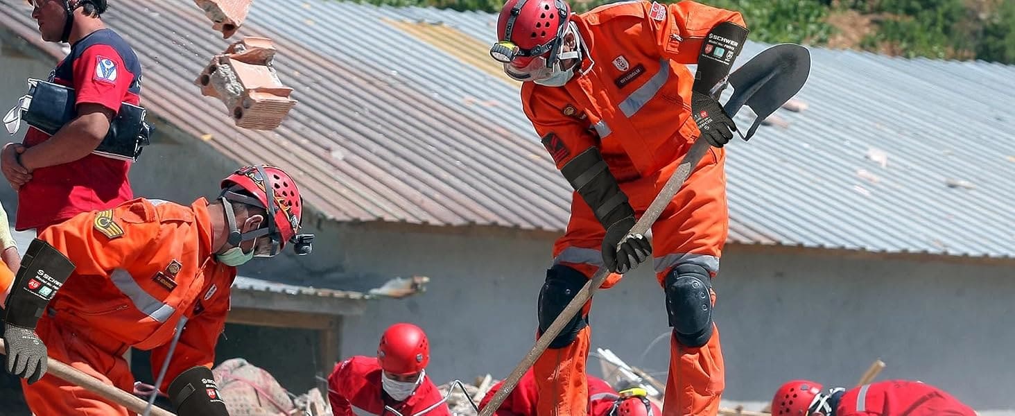 Rescue team in orange uniforms and helmets with shovels and axes on a building roof.