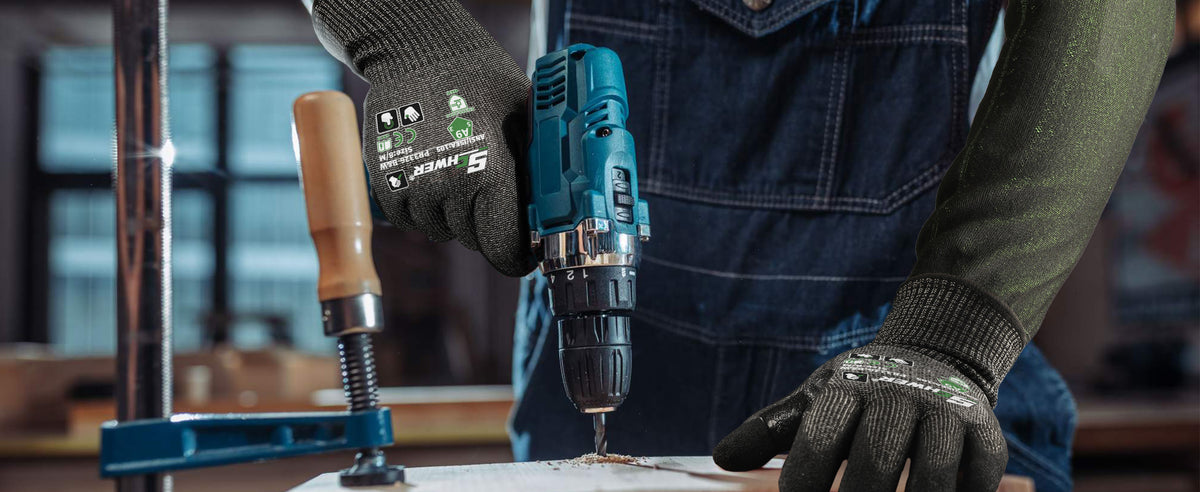 Person using a cordless drill with a focus on safety gear and tool