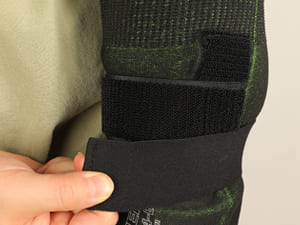 Close-up of a person holding a green and black boot with a strap.