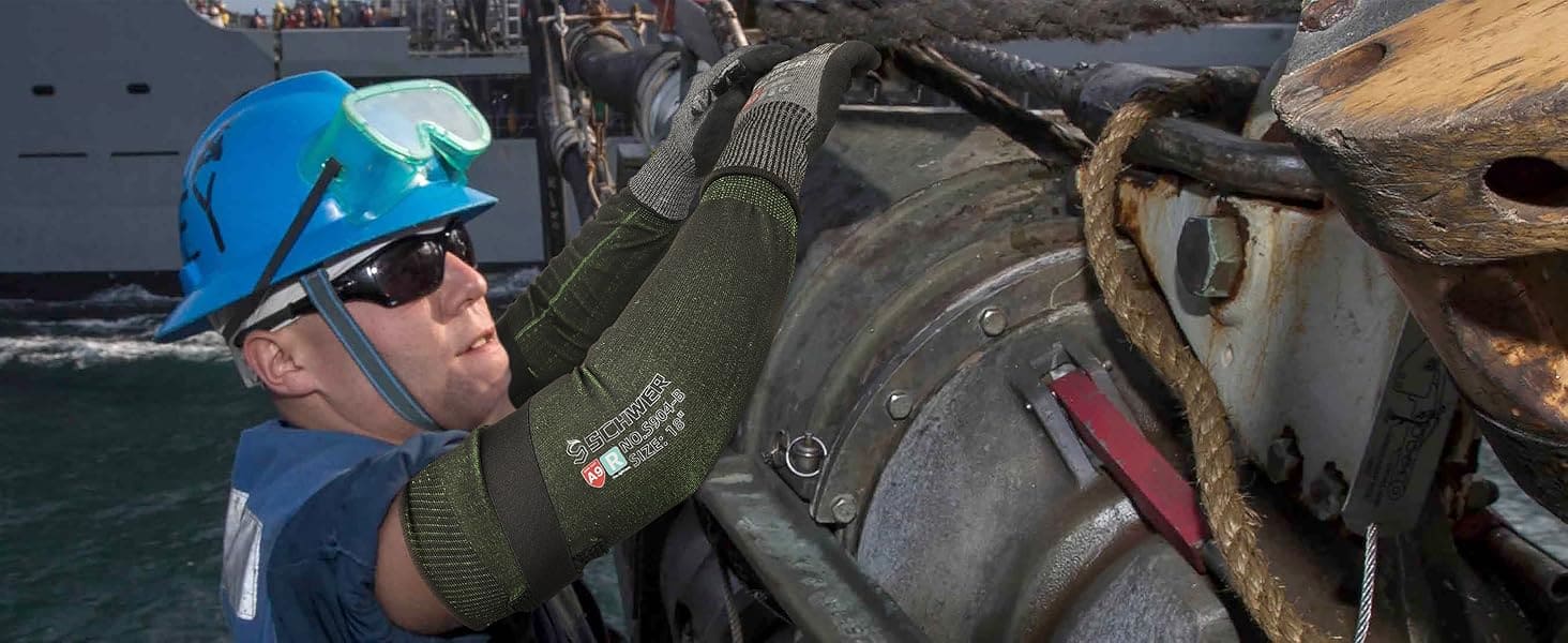 Person wearing a blue helmet and green gloves working on machinery.