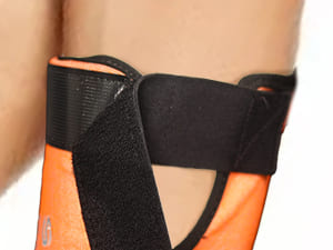 Close-up of a person wearing an orange and black wrist support brace.