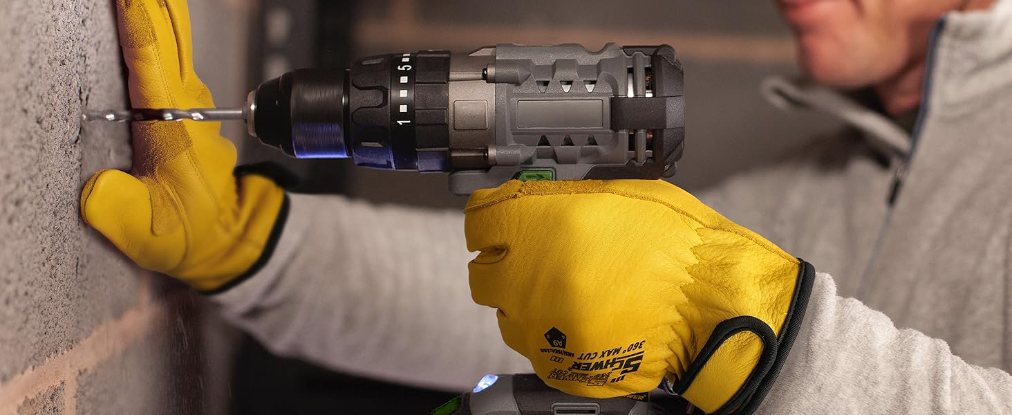 Person using a cordless drill on a wall with yellow gloves