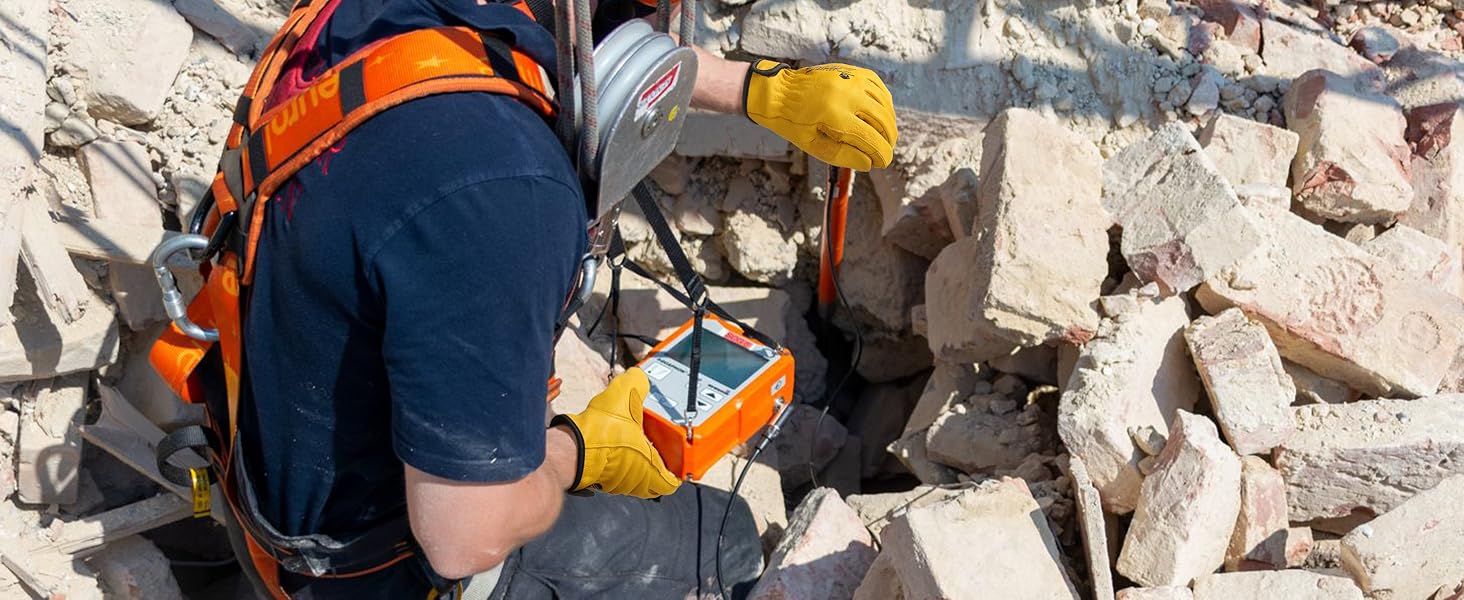 Person in safety gear using a device on rubble