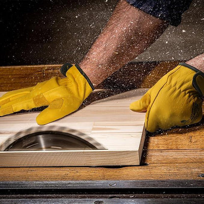 Worker using yellow protective work gloves while cutting wood on a table saw, PPE in use