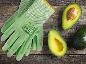 Green gardening gloves with textured palm, avocados cut in half on a wooden surface