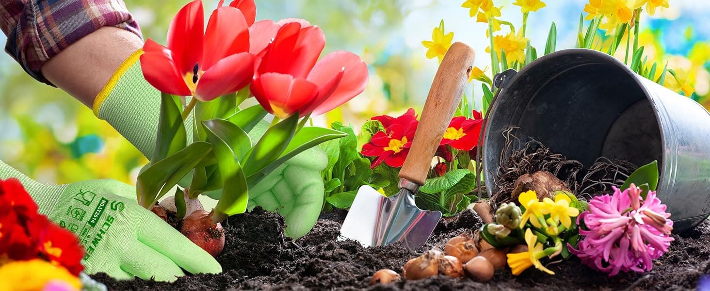 Gardening scene with red tulips, a trowel, and a garden hat amidst flowers and soil.
