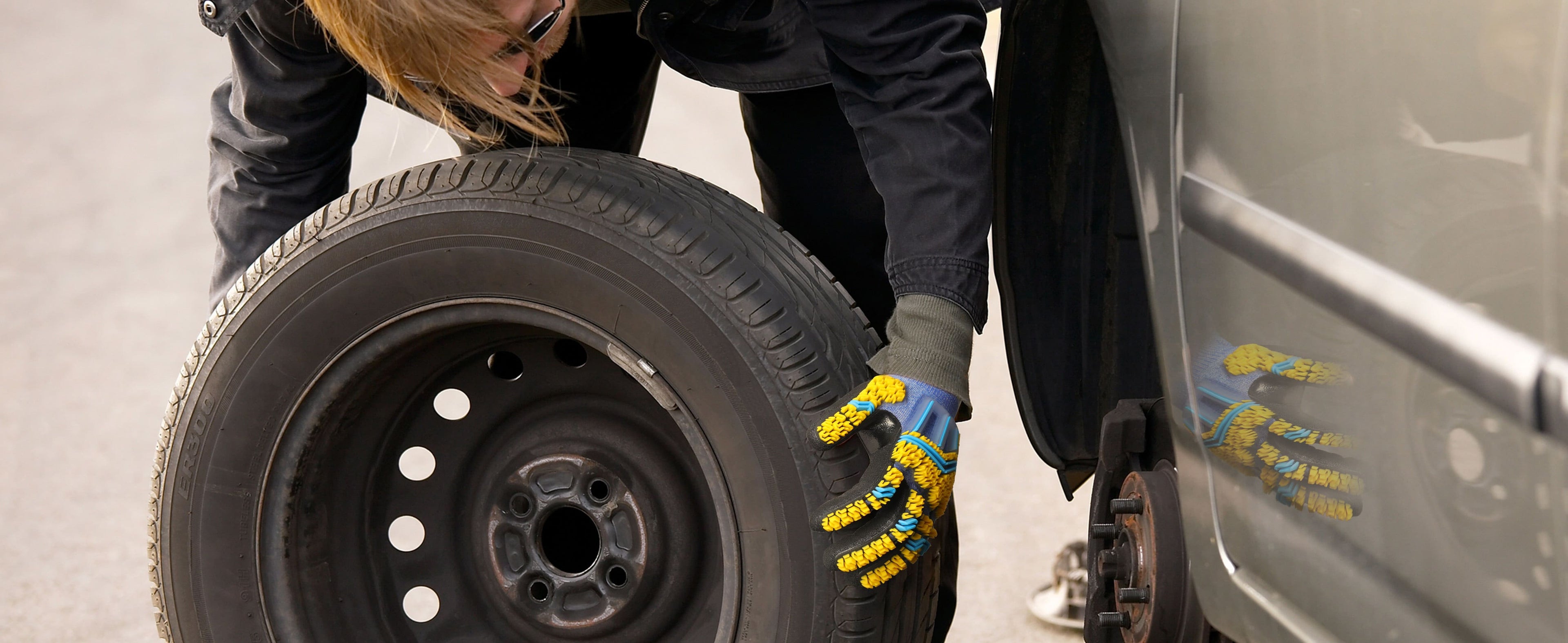 Person changing a tire on a vehicle with a focus on the tire and hands.
