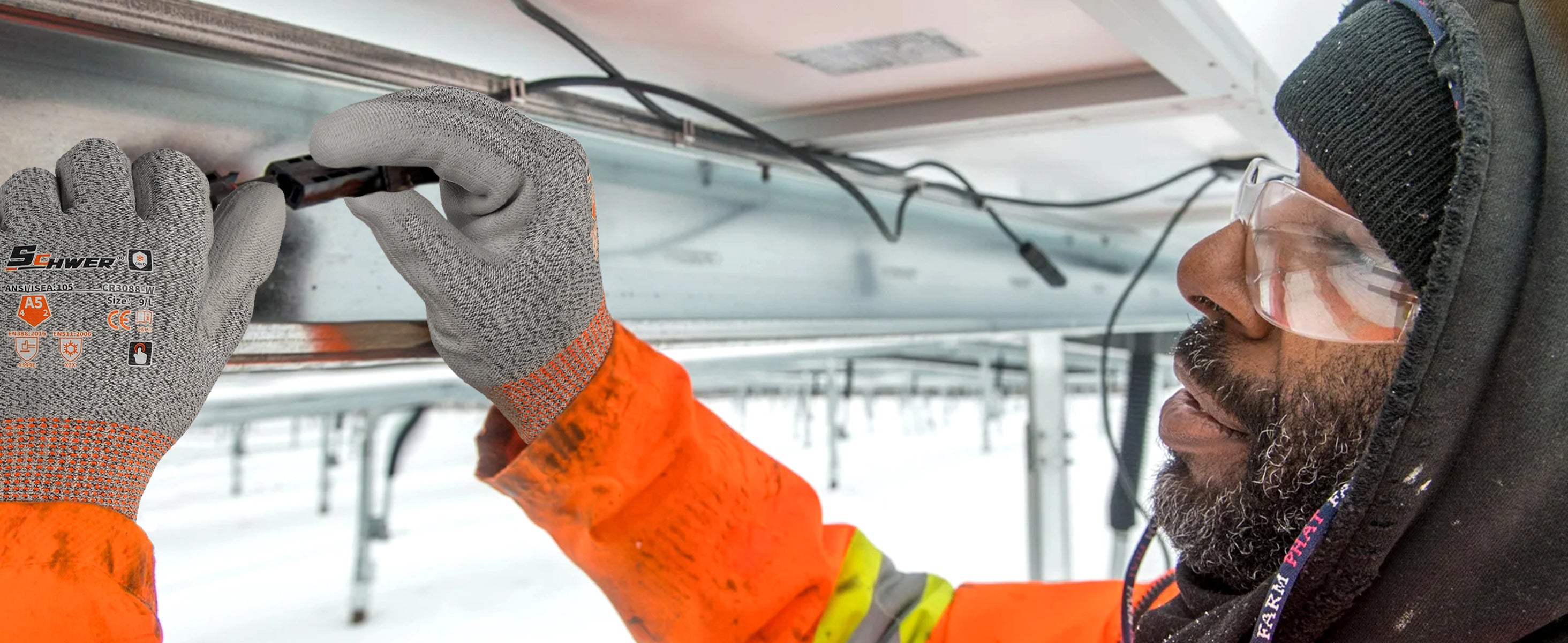 Person in orange safety jacket and gloves working on a vehicle interior with snow in the background