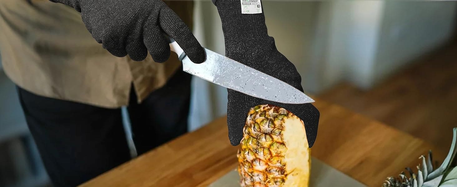 Person cutting a pineapple with a knife on a wooden table.