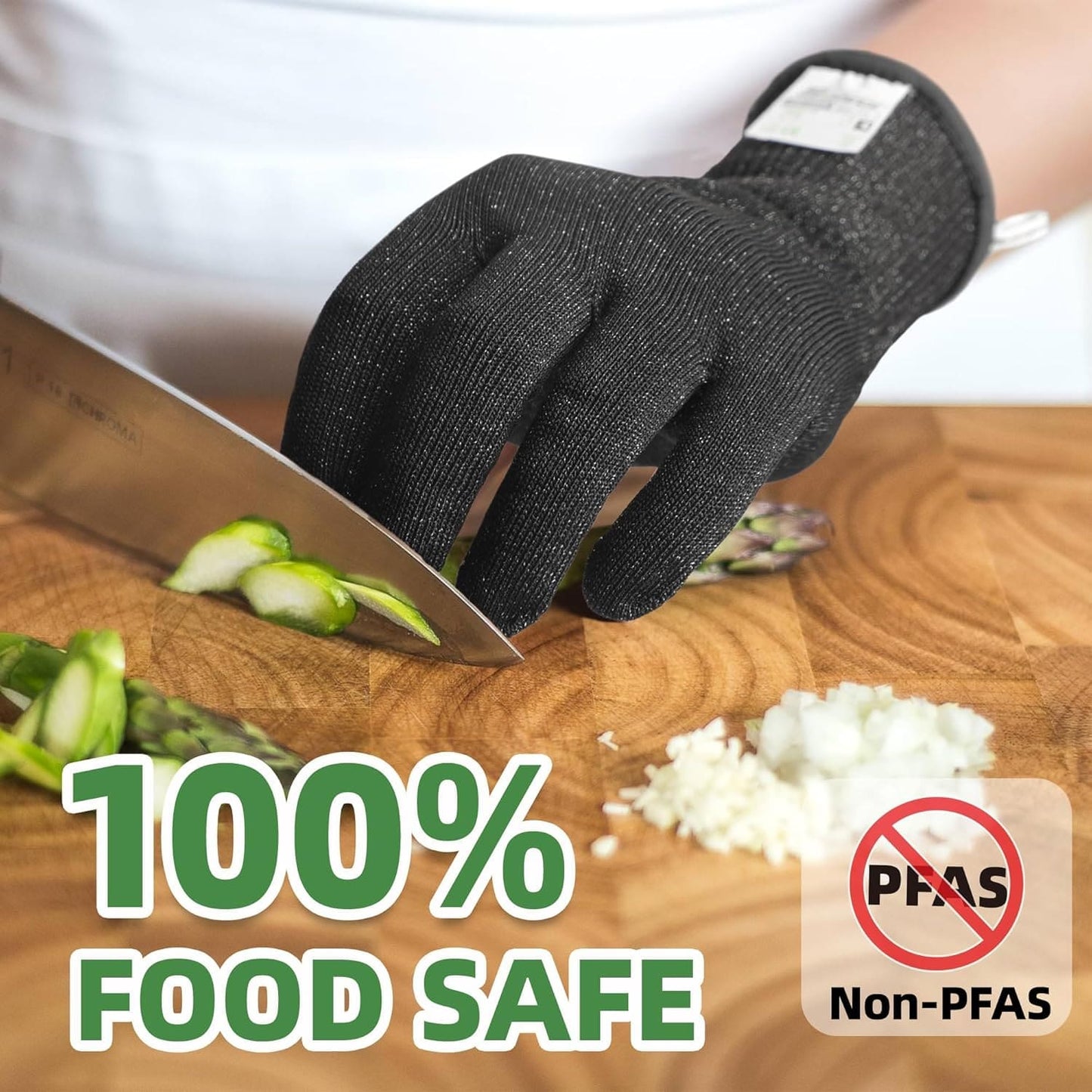 Black cut-resistant glove slicing asparagus on wooden cutting board labeled 100% food safe and non-PFAS