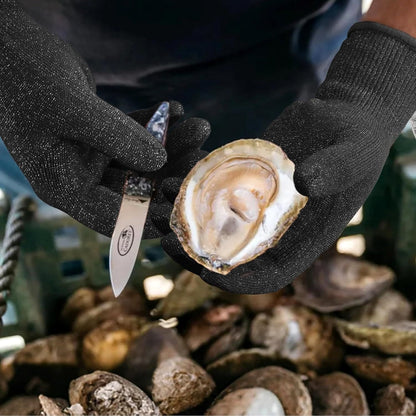 Hands in black gloves holding a shucked oyster and oyster knife over a crate of oysters