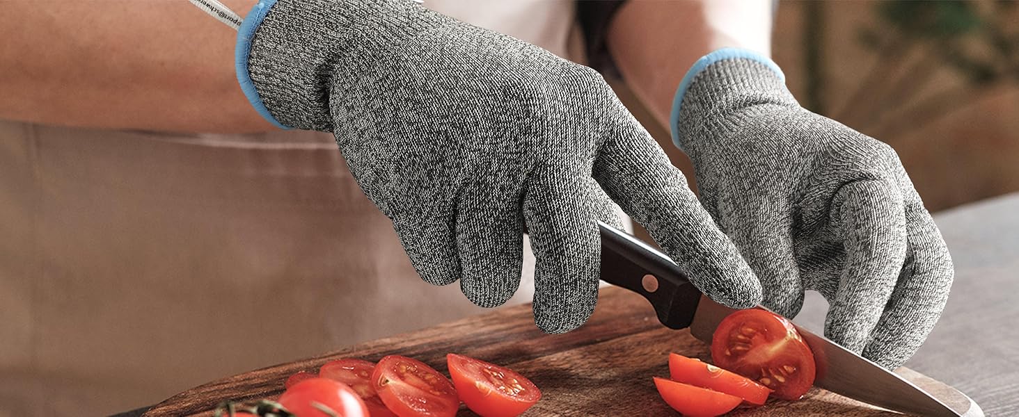 Person wearing gray gloves cutting tomatoes on a wooden board