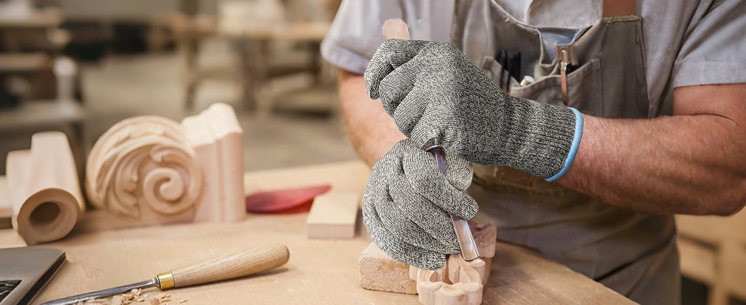 Person wearing cut-resistant gloves working with wood in a workshop.