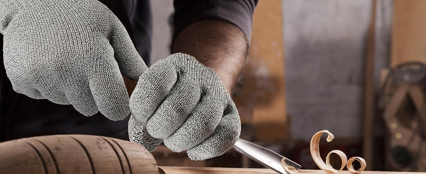 Person wearing gray gloves working with a tool on a wooden surface