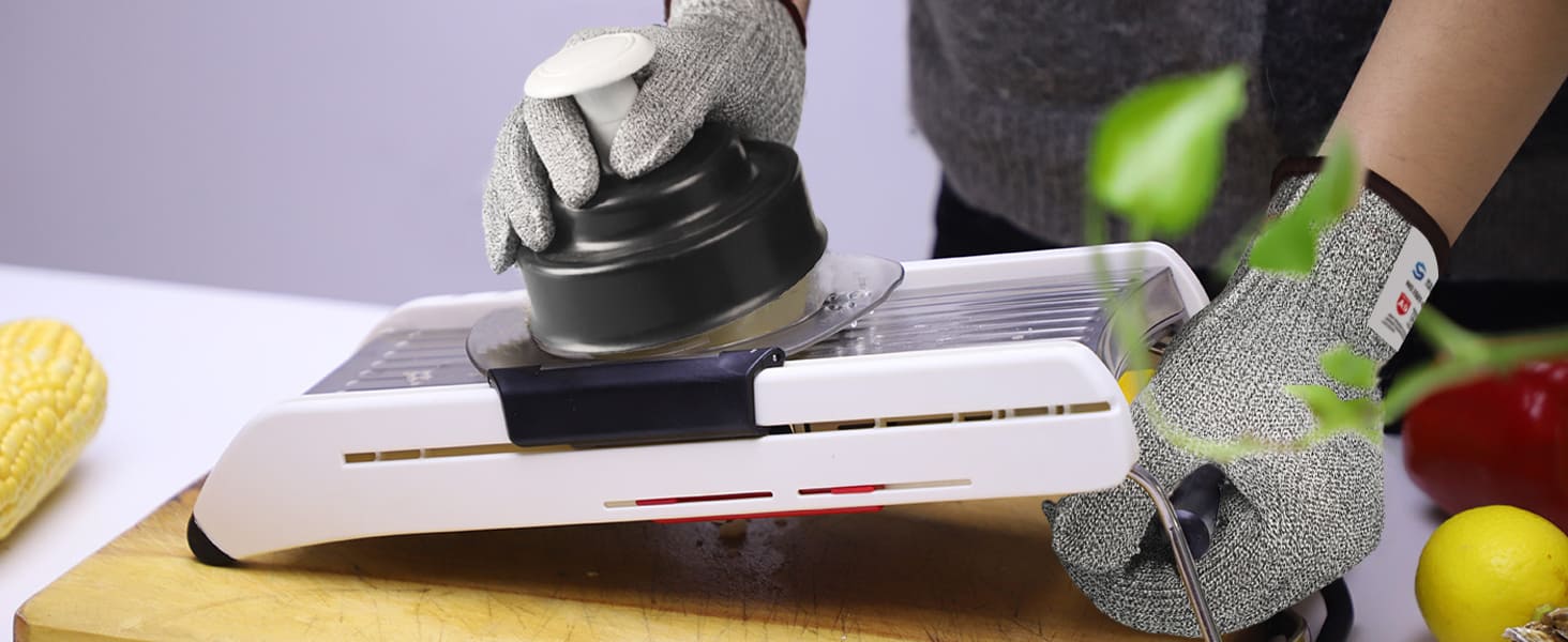 Person using a mandoline slicer on a cutting board with gloves on