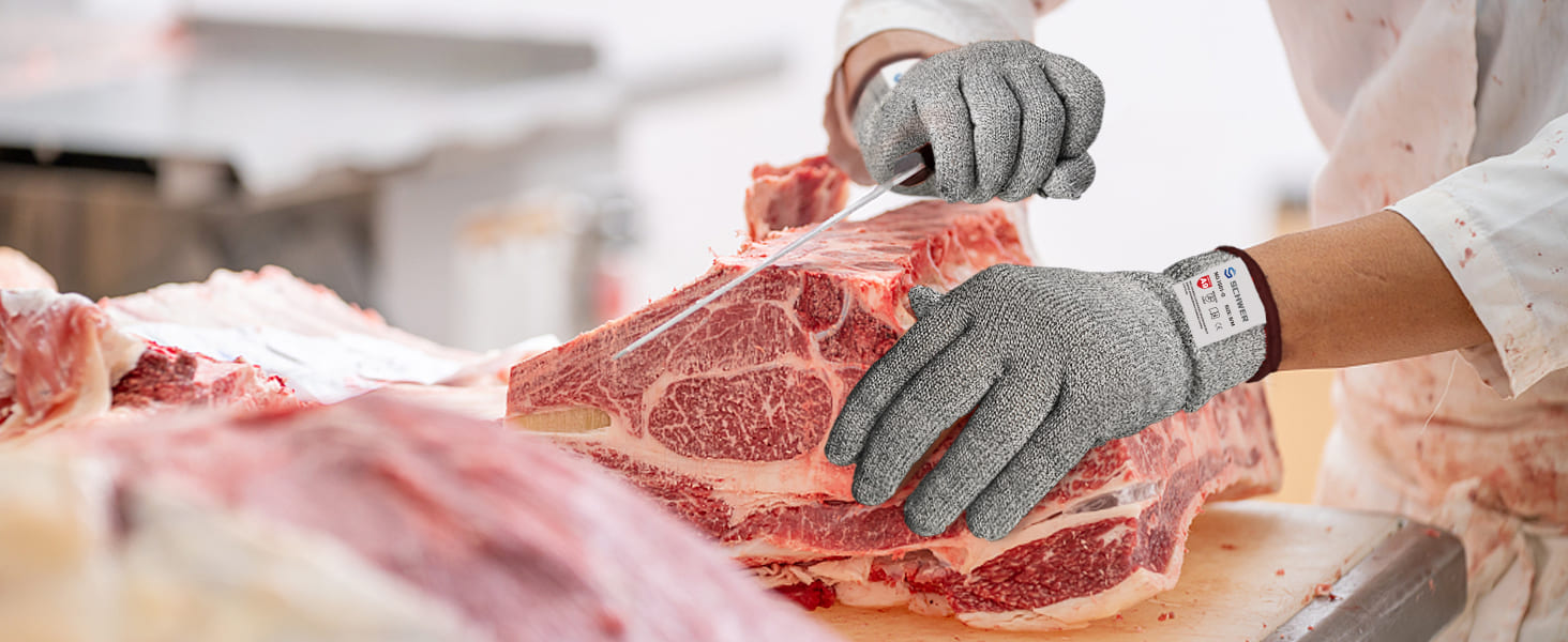 Person cutting meat with gloves on a butchery table