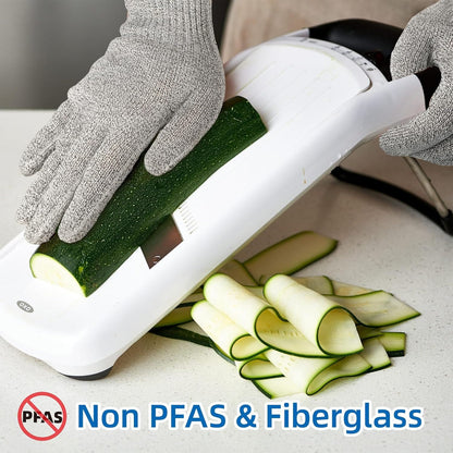 Person using a vegetable slicer to cut zucchini with gloves on, emphasizing non-PFAS and fiberglass material.