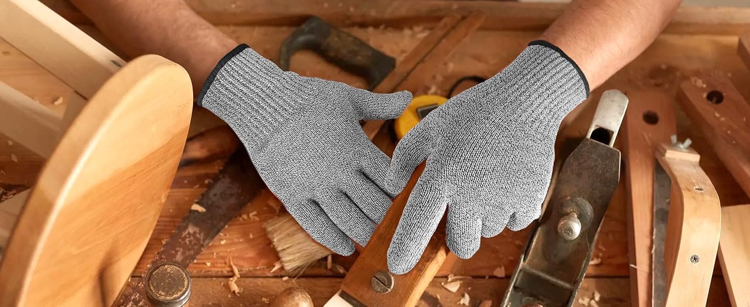 Gray gloves on a person's hands with a wooden background and tools.