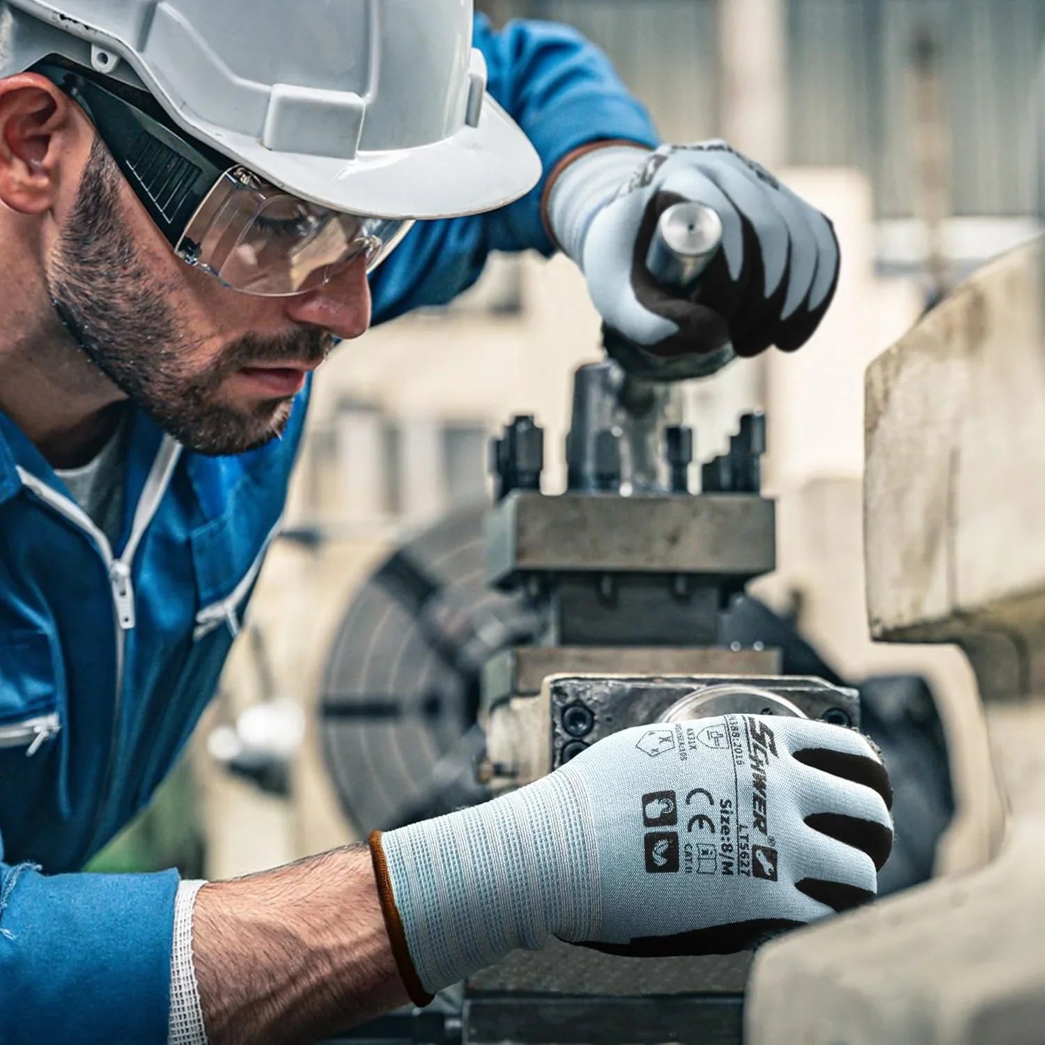 Worker wearing cut resistant Schwergloves and safety helmet operating industrial machine in factory