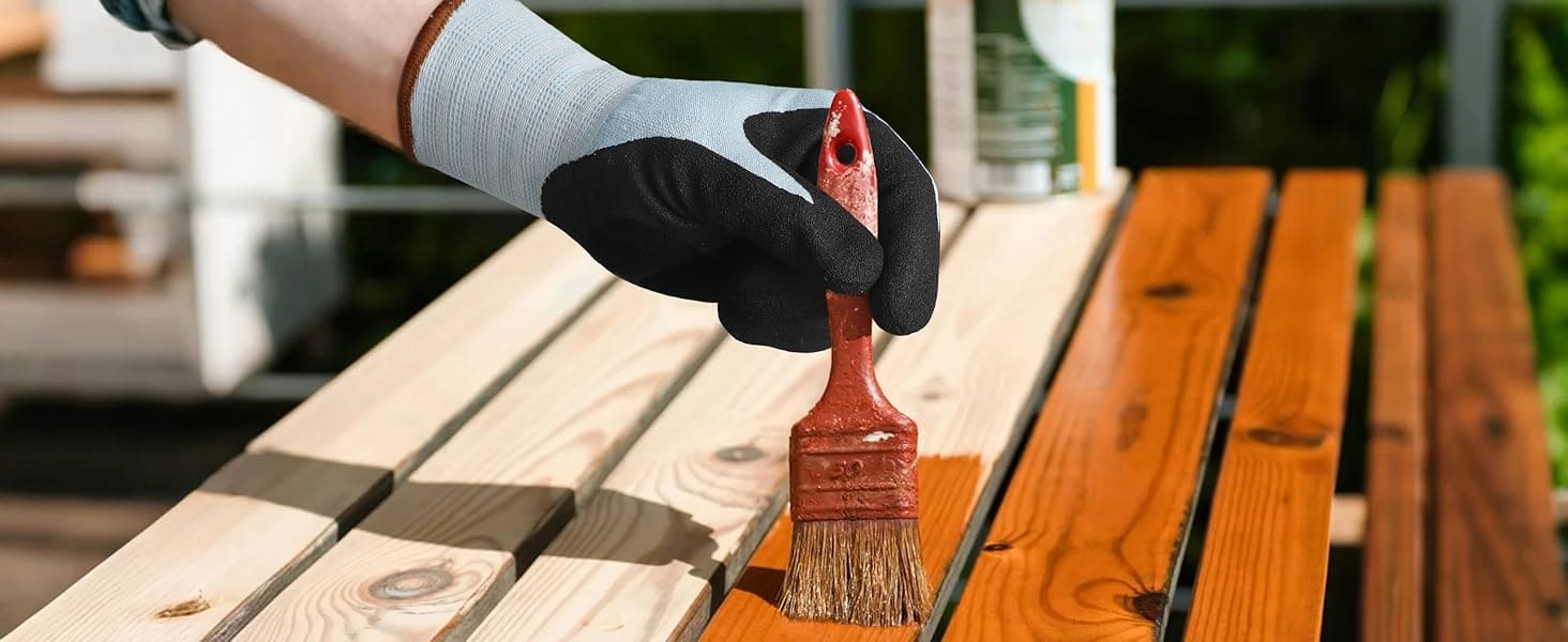 Person painting a wooden surface with a brush, wearing gloves.