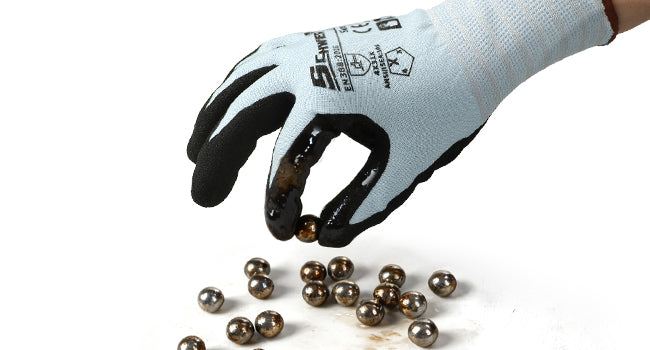Hand wearing a glove with black gloves holding metal balls on a white background