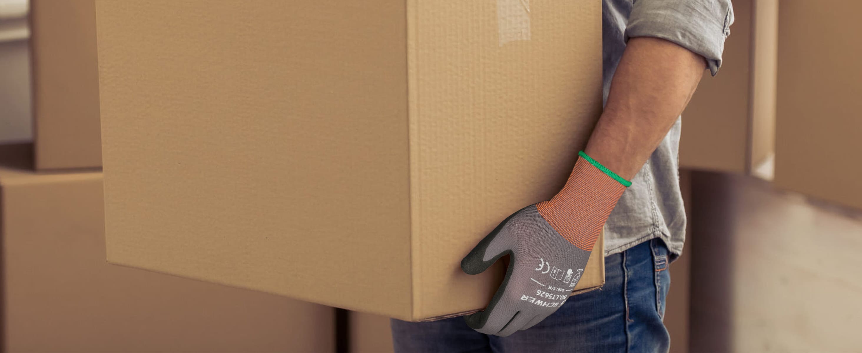 Person wearing gloves holding a cardboard box in an indoor setting