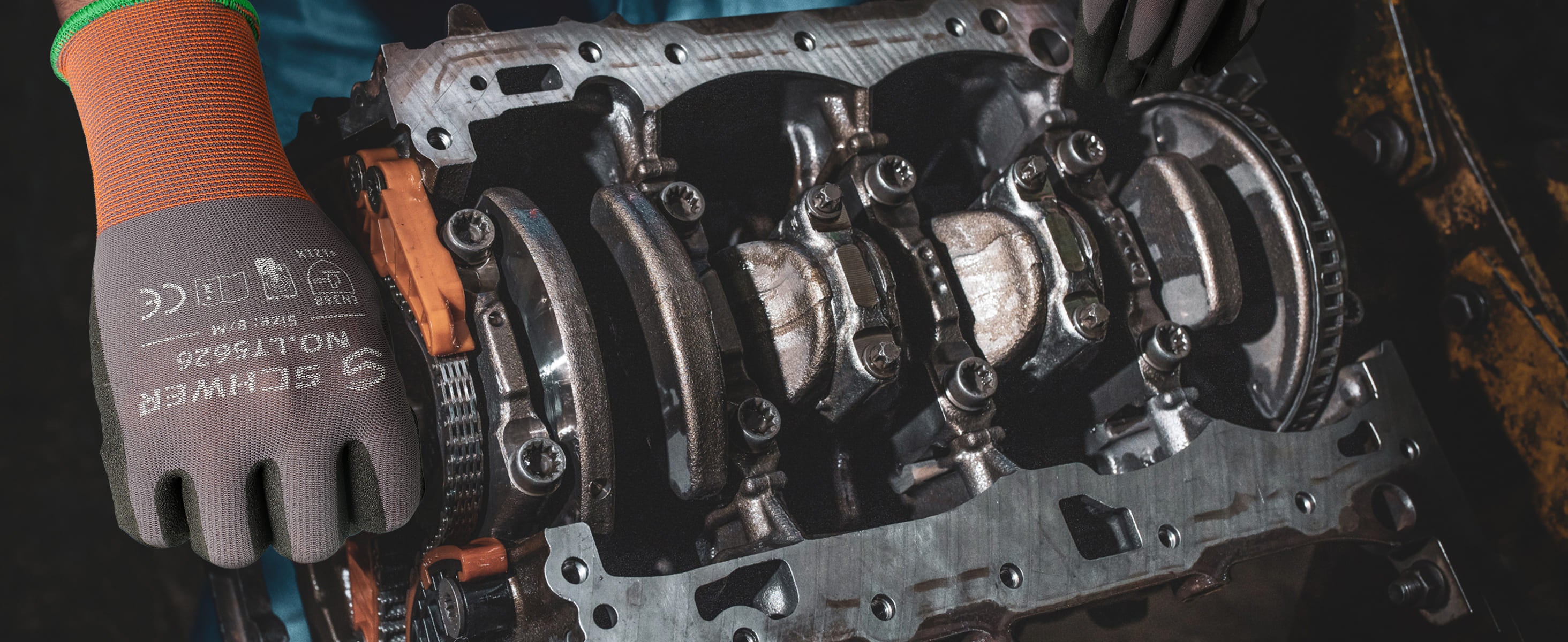 Engine block with mechanical parts and a gloved hand holding tools.