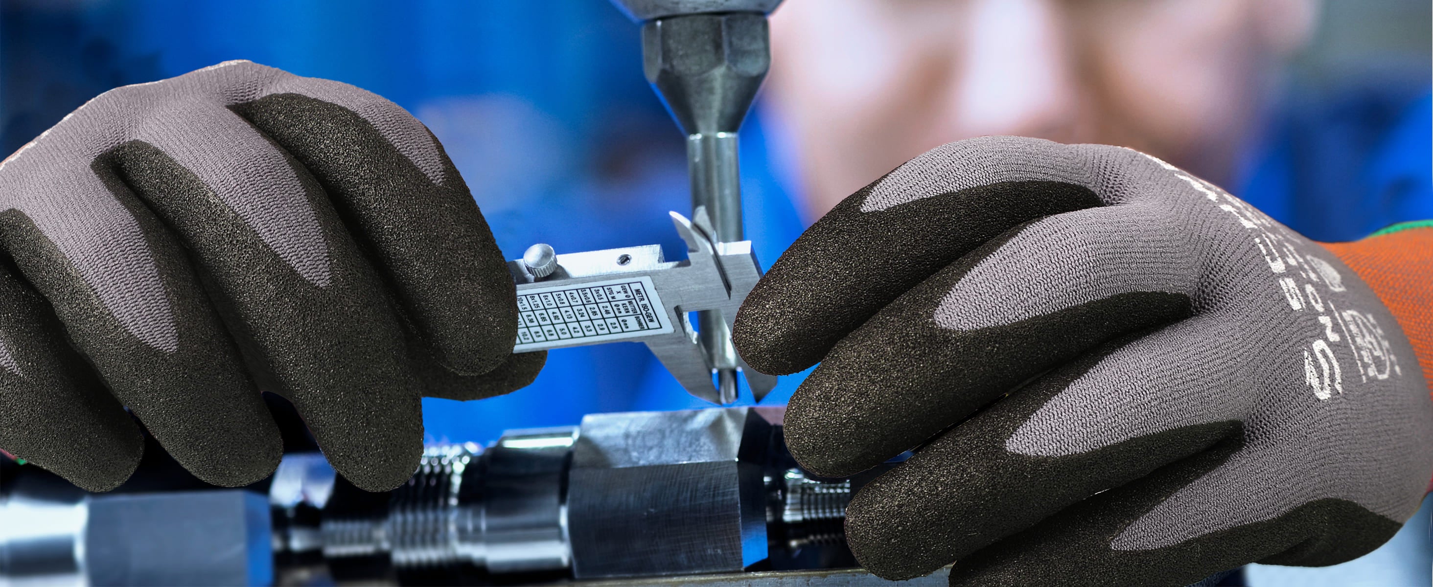 Close-up of hands wearing gloves using a tool on a blurred background