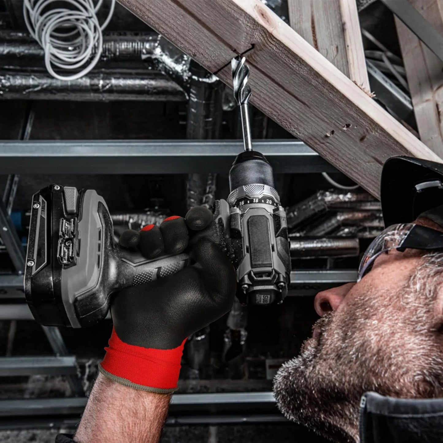 Man wearing Schwergloves black and red work gloves using a cordless drill on a wooden beam in construction setting
