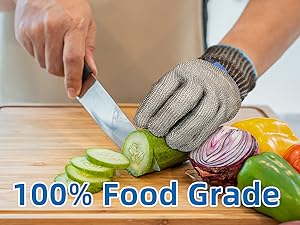 Person cutting vegetables with a knife on a wooden cutting board, wearing a food-grade glove.