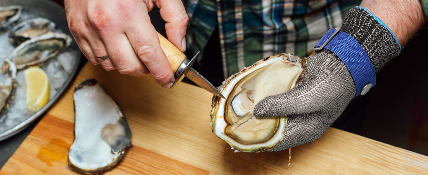 Person shucking an oyster on a wooden cutting board with a metal knife.
