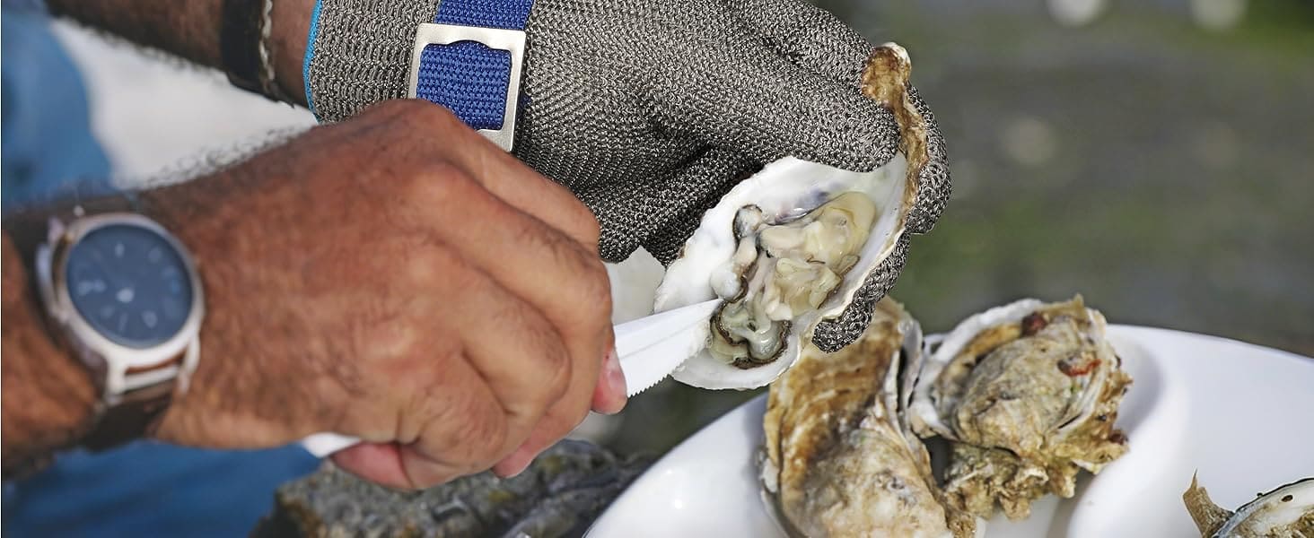 Person opening oysters with a knife on a white plate, with a blurred outdoor background.